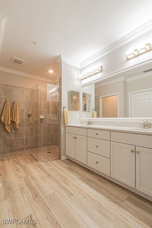 bathroom with crown molding, hardwood / wood-style floors, vanity, and a shower with shower door