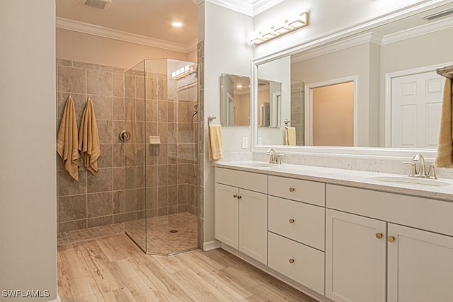 bathroom featuring wood-type flooring, ornamental molding, and tiled shower