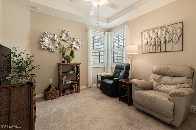 sitting room featuring a tray ceiling, ceiling fan, and light colored carpet