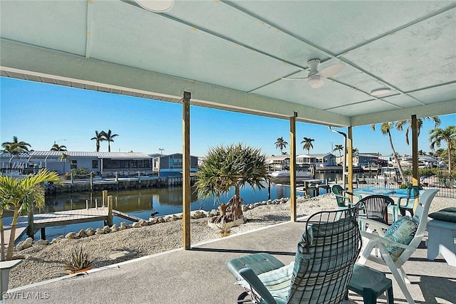 view of patio with ceiling fan, a water view, and a boat dock