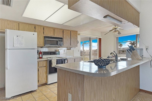 kitchen with kitchen peninsula, ceiling fan, white appliances, and a wealth of natural light