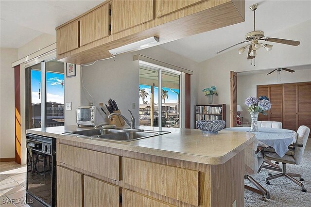 kitchen featuring ceiling fan, dishwasher, sink, light carpet, and light brown cabinetry