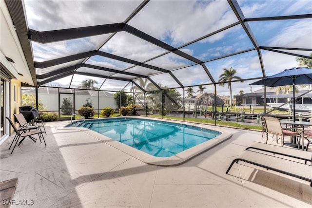 view of pool with glass enclosure, a patio area, and a grill