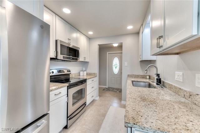 kitchen with light stone counters, sink, white cabinets, and stainless steel appliances