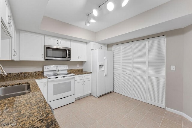 kitchen featuring white appliances, white cabinetry, dark stone counters, and sink