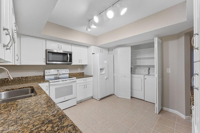 kitchen featuring white appliances, white cabinetry, dark stone countertops, and sink