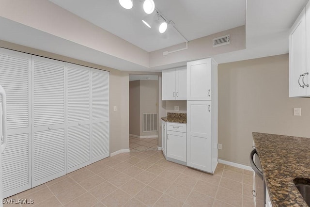 kitchen featuring white cabinetry, light tile patterned floors, and dark stone counters