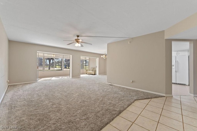 spare room with ceiling fan with notable chandelier and light carpet