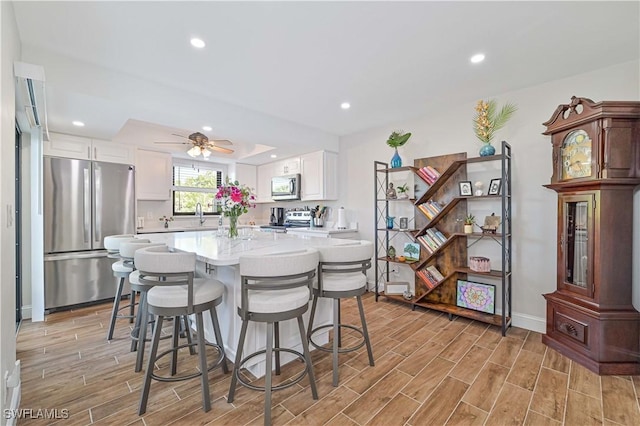 kitchen featuring white cabinets, a breakfast bar, stainless steel appliances, and ceiling fan