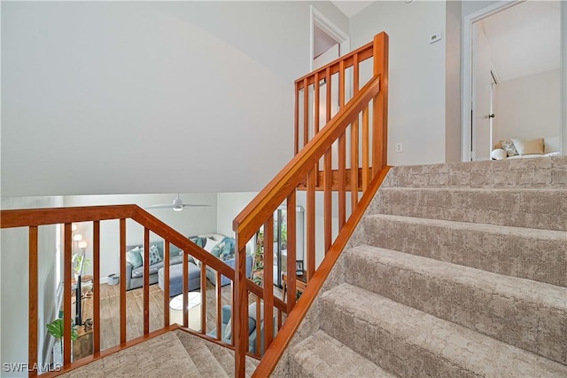 stairs with ceiling fan and lofted ceiling