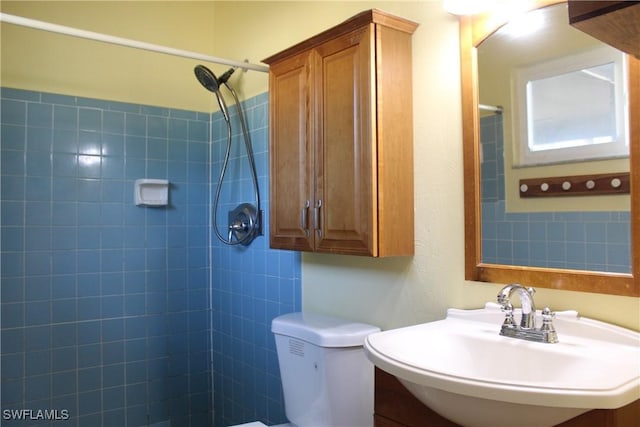 bathroom featuring sink, tiled shower, and toilet