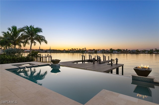 pool at dusk featuring a dock and a water view