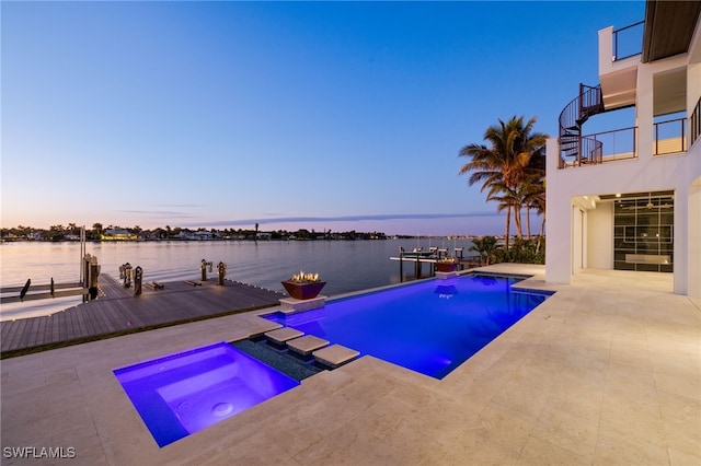 pool featuring a water view, a dock, a patio, and an in ground hot tub