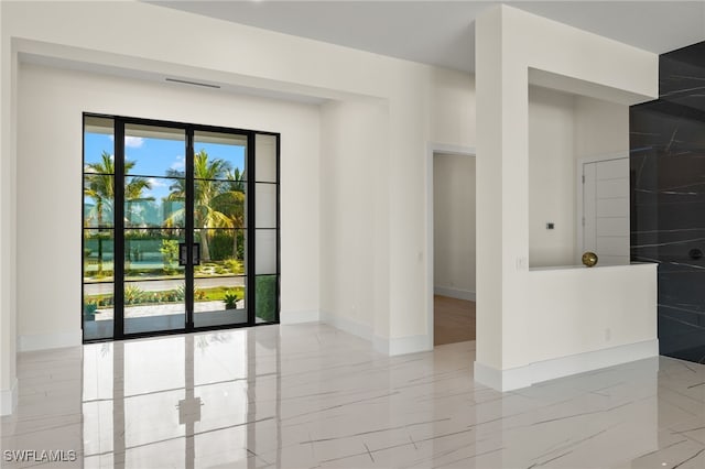 empty room with marble finish floor, visible vents, and baseboards