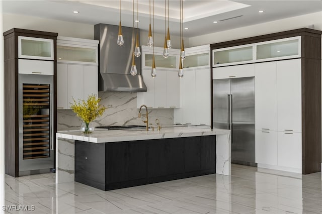 kitchen with light stone countertops, modern cabinets, high quality fridge, and exhaust hood