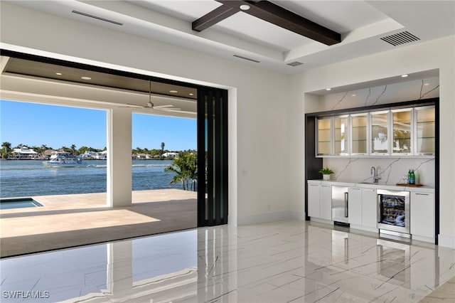 interior space with marble finish floor, indoor wet bar, beam ceiling, visible vents, and beverage cooler