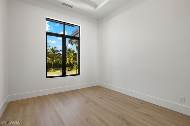 unfurnished room with light wood-type flooring, visible vents, and baseboards