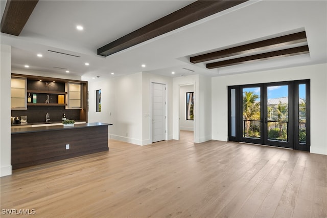 unfurnished living room featuring light wood-style flooring, recessed lighting, baseboards, beam ceiling, and wet bar