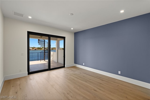 unfurnished room with recessed lighting, a water view, visible vents, baseboards, and light wood-type flooring