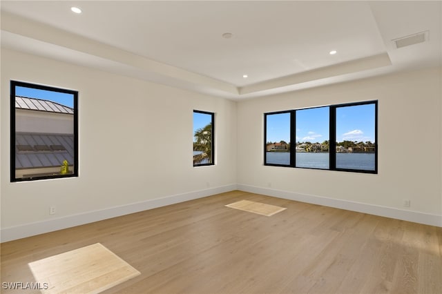 unfurnished room featuring baseboards, recessed lighting, a raised ceiling, and light wood-style floors