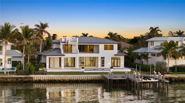 rear view of property featuring metal roof, a standing seam roof, a water view, and boat lift