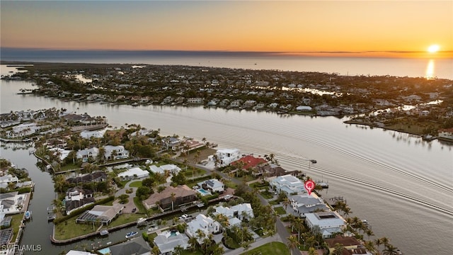 aerial view at dusk featuring a water view and a residential view