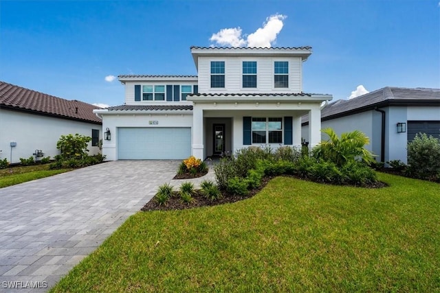 mediterranean / spanish-style house with a garage, decorative driveway, a front yard, and a tile roof