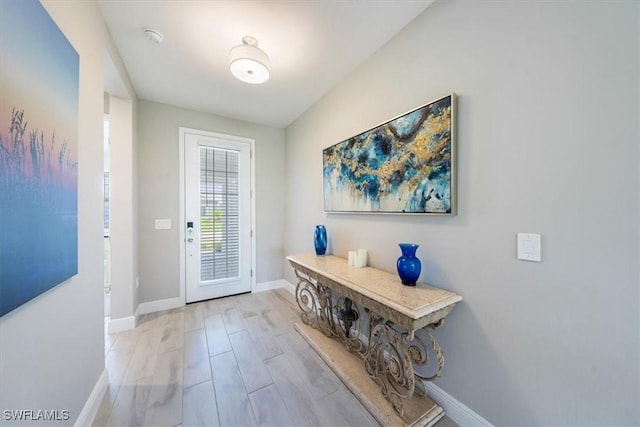 doorway with light wood-style floors and baseboards