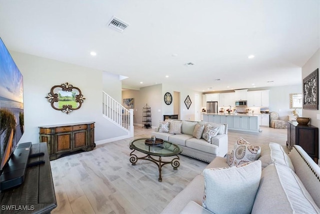 living area with light wood finished floors, visible vents, stairway, and recessed lighting