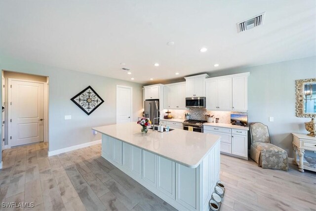 4016 Pegasus Way, Naples, FL 34120 - kitchen with appliances with stainless steel finishes, an island with sink, white cabinets, decorative backsplash, and recessed lighting