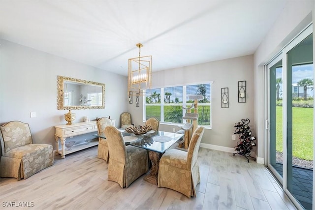 dining area featuring baseboards, a healthy amount of sunlight, a notable chandelier, and light wood finished floors