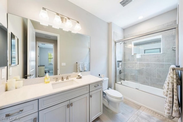 bathroom with visible vents, shower / bath combination with glass door, vanity, and toilet