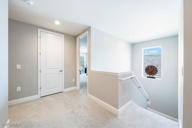 corridor featuring light carpet, recessed lighting, baseboards, and an upstairs landing