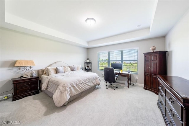 bedroom with light carpet and a tray ceiling