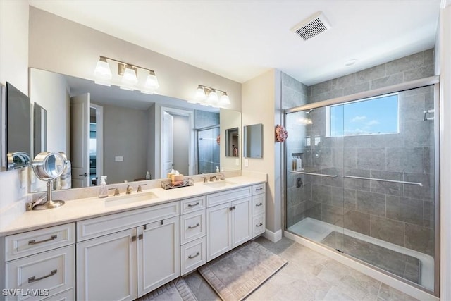 bathroom featuring visible vents, a sink, a shower stall, and double vanity