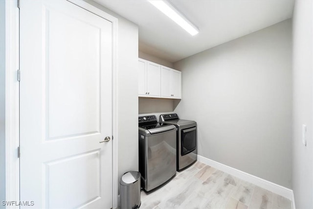 washroom featuring baseboards, washing machine and dryer, cabinet space, and light wood-style floors