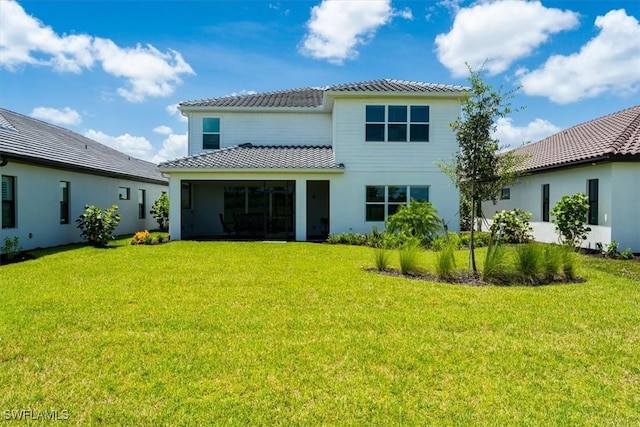 back of house featuring a tile roof and a yard