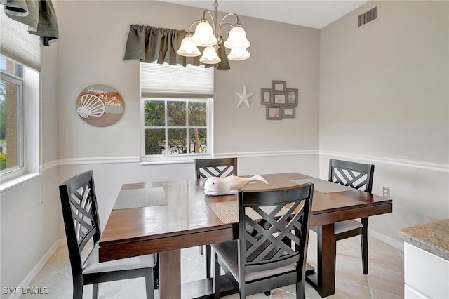 dining space with a wealth of natural light, light tile patterned floors, and an inviting chandelier