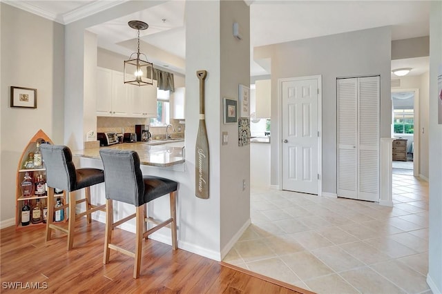 kitchen featuring kitchen peninsula, plenty of natural light, white cabinets, and hanging light fixtures