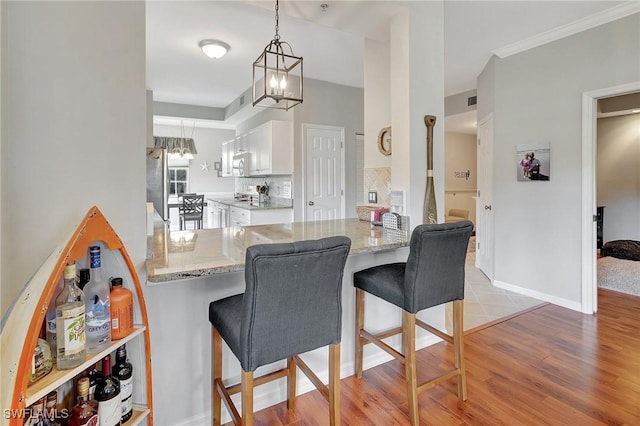 kitchen featuring hanging light fixtures, kitchen peninsula, stove, a kitchen bar, and white cabinets