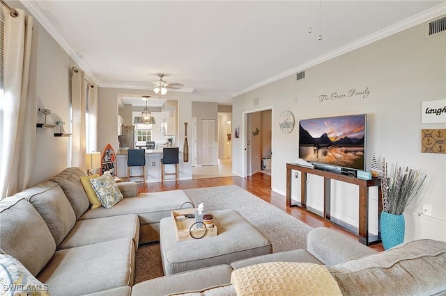 living room featuring hardwood / wood-style floors, ceiling fan, and ornamental molding