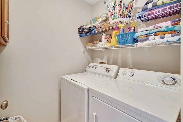 clothes washing area featuring washer and dryer and cabinets