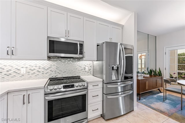 kitchen featuring light tile patterned flooring, stainless steel appliances, backsplash, and white cabinets