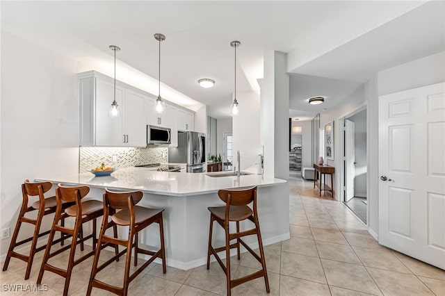 kitchen with sink, decorative light fixtures, kitchen peninsula, stainless steel appliances, and decorative backsplash