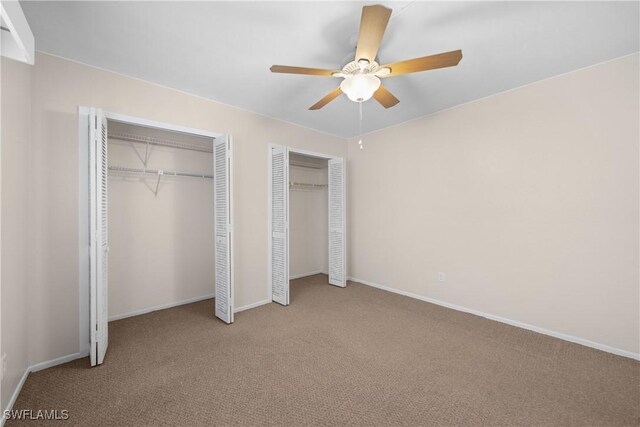 unfurnished bedroom featuring light carpet, two closets, and ceiling fan