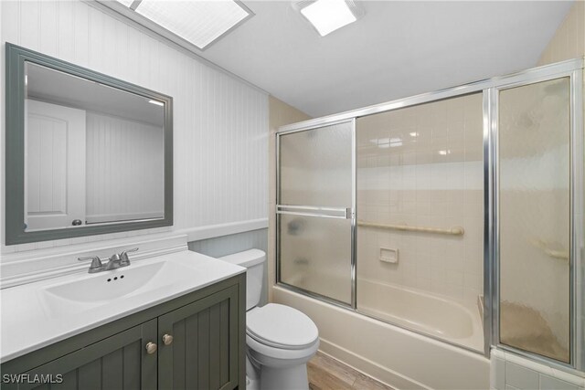 full bathroom with vanity, toilet, shower / bath combination with glass door, and wood-type flooring