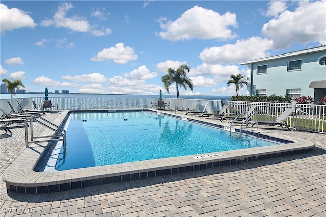 view of swimming pool with a patio area and a water view