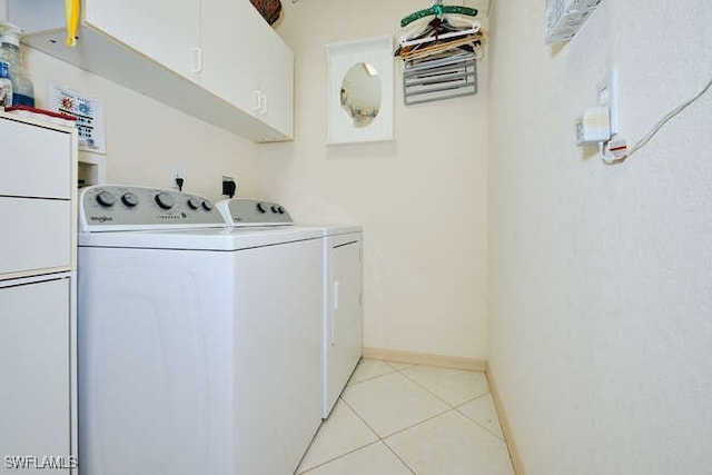 laundry area with light tile patterned flooring, cabinets, and washer and dryer