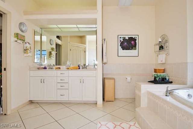 bathroom featuring a relaxing tiled tub, vanity, and tile patterned flooring