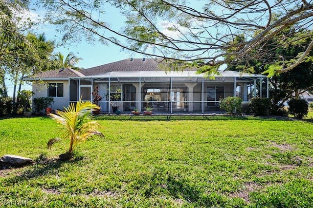 back of property with a lawn and glass enclosure